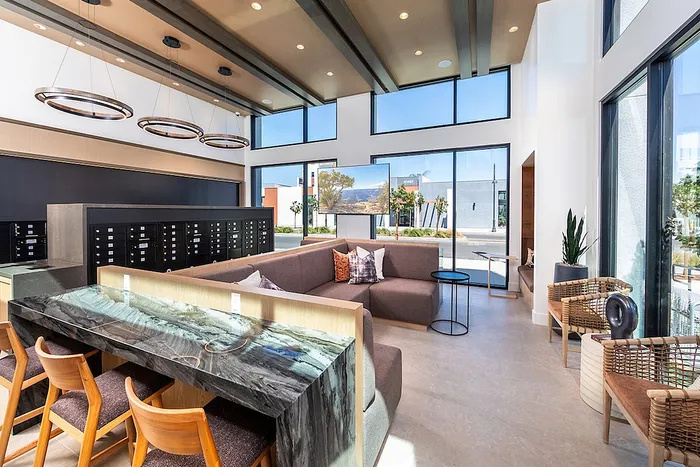 Contemporary apartment co-working lounge with panoramic windows, stylish seating, and chic lighting fixtures, creating an inviting and modern atmosphere.