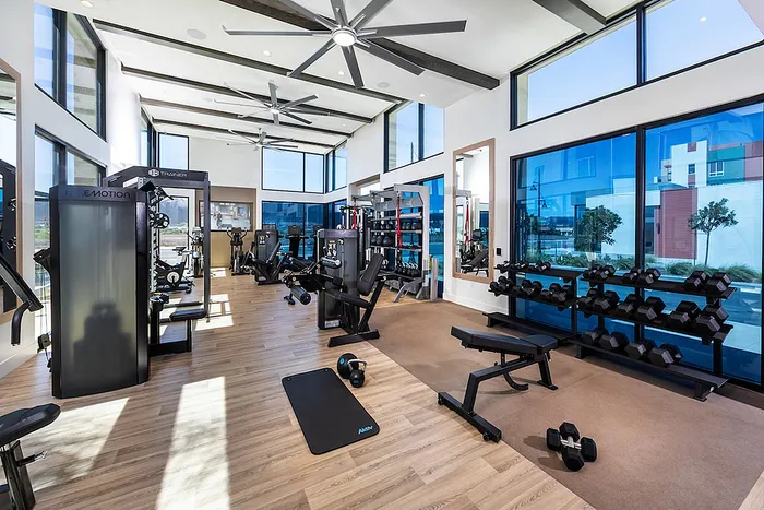 Bright and modern gym with state-of-the-art fitness equipment, large windows, and stylish wooden flooring.