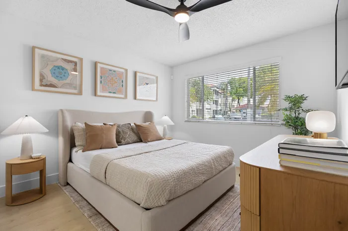 Elegant bedroom with a cozy bed, modern decor, and ample natural light from a large window, creating a serene and inviting atmosphere.