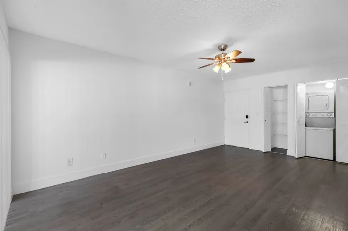 Bright living space with modern wood flooring, ceiling fan, and convenient in-unit laundry closet.