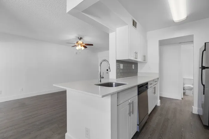 Sleek modern kitchen with an open concept, featuring a stylish breakfast bar, stainless steel appliances, and wood flooring.