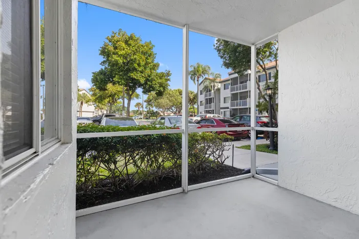 Bright, inviting patio with white walls overlooking a landscaped garden and modern apartment complex.
