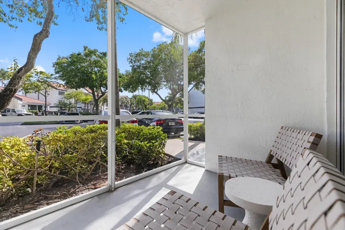 Inviting screened patio with comfortable seating overlooking lush greenery and a serene neighborhood view.