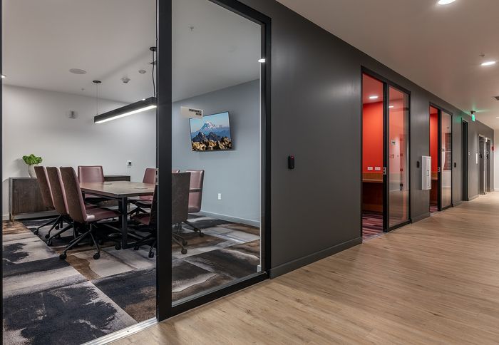 Modern conference room with sleek glass doors, stylish seating, and vibrant wall accents, offering a professional and inviting space.