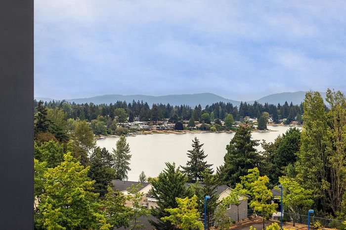 Breathtaking panoramic view of a tranquil Angle lake surrounded by lush greenery and distant mountains, offering serene living and natural beauty.