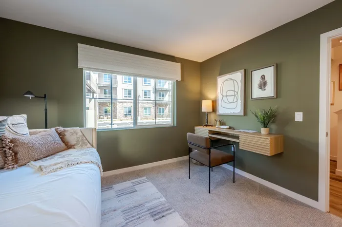 Bright and cozy home office with a modern desk, plush seating, and large window offering a scenic view.
