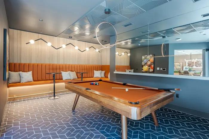 Chic game room featuring a stylish pool table, cozy orange seating, and modern decor for a perfect entertainment space.