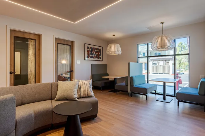 Modern co-working lounge with sleek booth seating, contemporary lighting, and stylish decor, exuding warmth and inviting comfort.