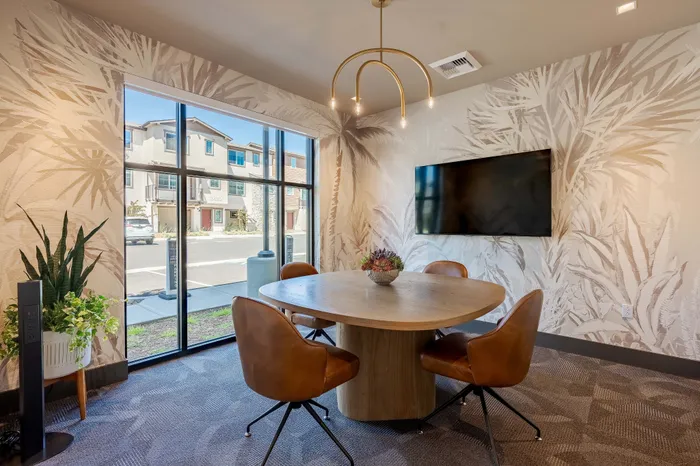 Chic conference room with a round table, leather chairs, and stylish wallpaper. Large windows bring in natural light, highlighting the sophisticated d&eacute;cor.