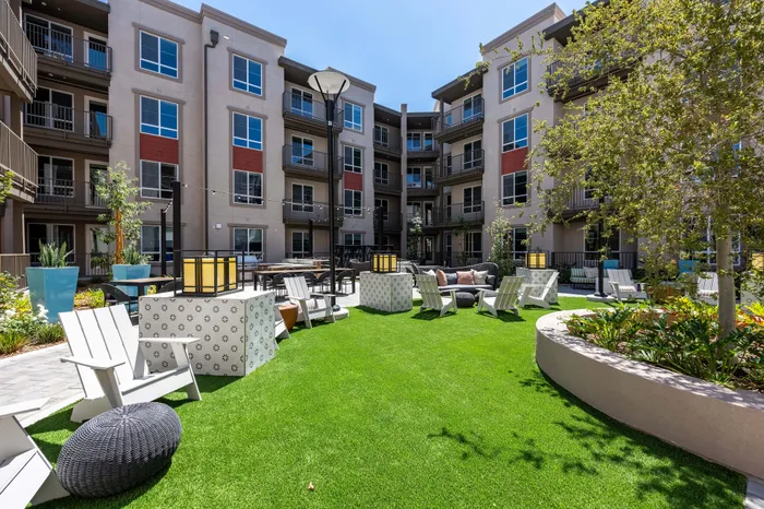 Charming apartment courtyard with lush green lawn, modern seating, and stylish backdrop.