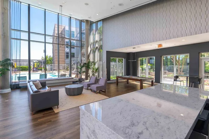 Luxurious modern lounge with floor-to-ceiling windows, pool view, and elegant seating, perfect for relaxation.