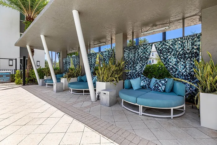 Chic outdoor lounge area with turquoise seating and vibrant patterned drapes, offering a stylish retreat with lush greenery and modern design.