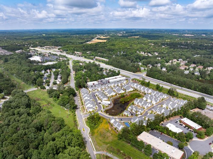 Aerial view of a picturesque residential community surrounded by lush greenery and expansive roads, capturing serene suburban living.