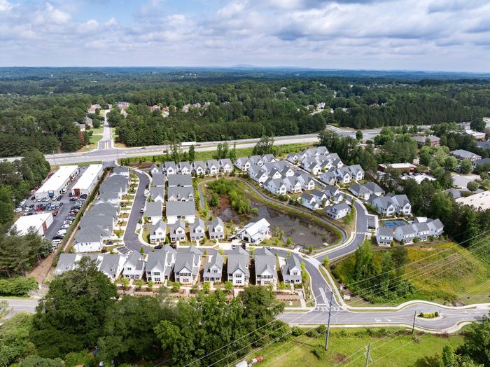 Charming suburban enclave with modern townhouses nestled among lush greenery, featuring scenic pathways and a tranquil pond.