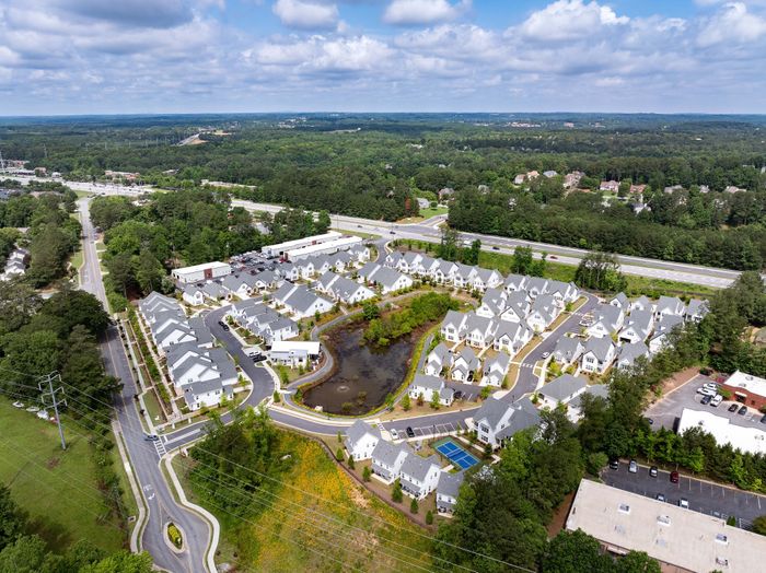 Scenic aerial view of a charming residential community with modern homes, lush greenery, and peaceful surroundings, perfect for comfortable living.