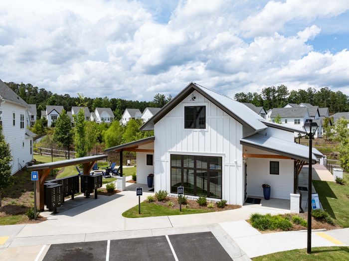 Charming white farmhouse-style community center with lush greenery, modern amenities, and serene surroundings.