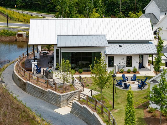 Charming riverside clubhouse with a spacious deck and cozy fire pit surrounded by lush greenery.