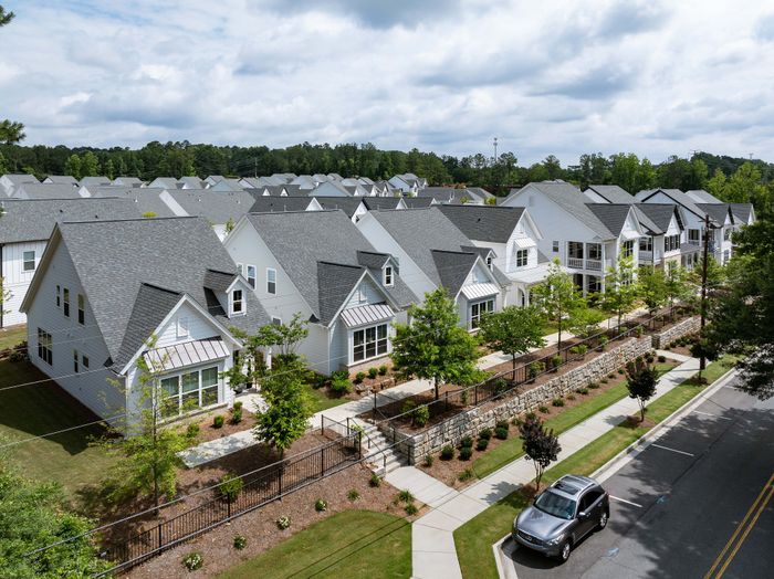 Charming suburban neighborhood with modern white houses, manicured lawns, and tree-lined sidewalks in a serene setting.