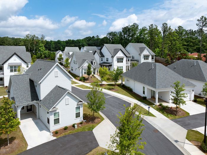 Charming suburban neighborhood with modern white houses, lush greenery, and well-maintained roads.