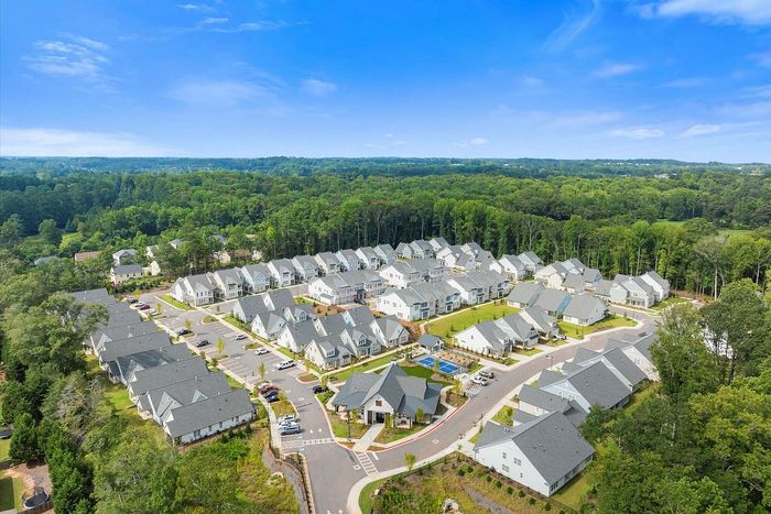 Aerial view of a picturesque suburban community with neatly arranged houses, vibrant greenery, and clear blue skies.
