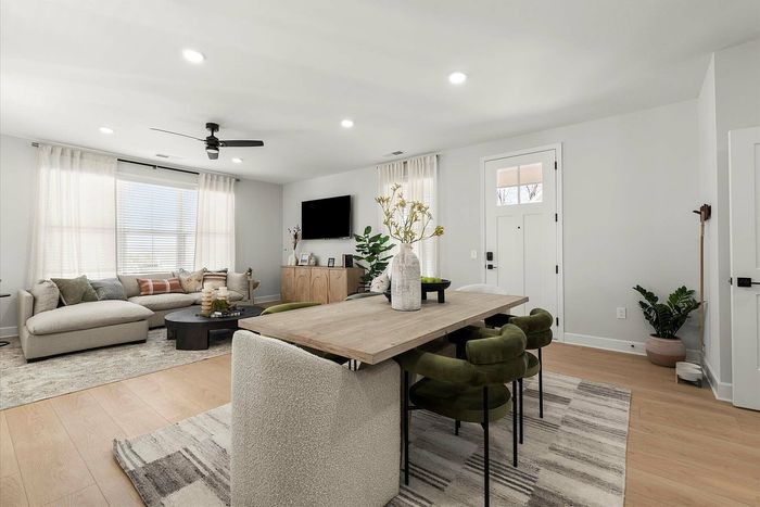 Bright, modern living room with elegant furniture, featuring a cozy sectional sofa, stylish dining area, and decorative plants for a serene atmosphere.