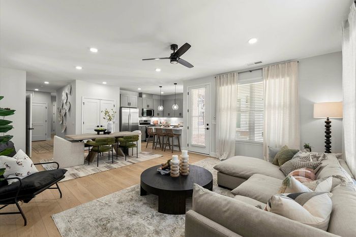 Modern open-concept living room with plush seating, stylish dining area, and sleek kitchen with stainless steel appliances.