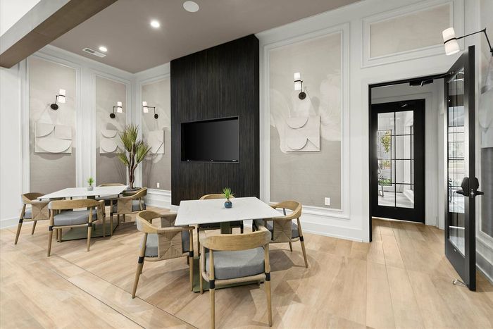 Elegant apartment lounge with modern decor, featuring stylish wooden furniture, wall art, and a sleek TV setup.