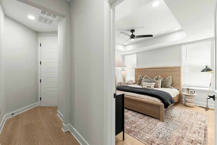Inviting bedroom with a cozy modern design, featuring a plush bed, elegant ceiling fan, and warm wooden accents.