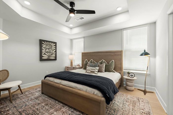 Bright and inviting bedroom showcasing elegant decor, a stylish wooden bed frame, and large windows with ample natural light.