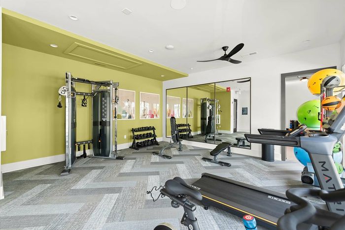 Modern apartment gym featuring state-of-the-art equipment, colorful walls, and natural lighting for an invigorating workout experience.