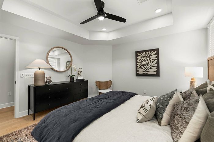 Elegant bedroom with modern decor, featuring a plush bed, stylish artwork, and a sleek dresser under ambient lighting.