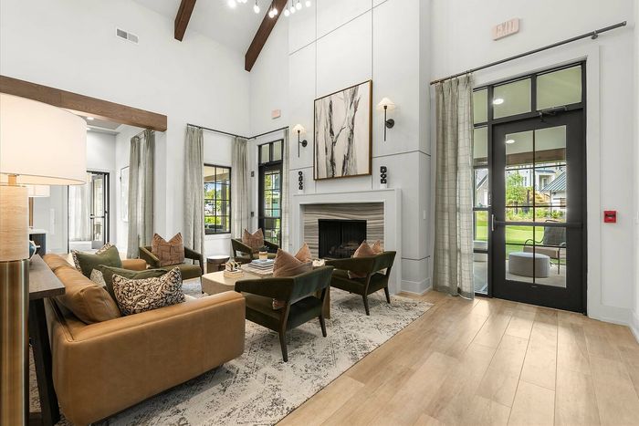 Elegant living room with high ceilings, cozy seating, and a modern fireplace, accentuated by large windows and natural light.