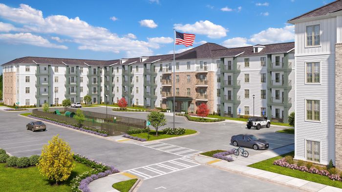Elegant apartment complex with modern architecture, lush landscaping, and spacious parking, featuring a vibrant American flag under a clear blue sky.