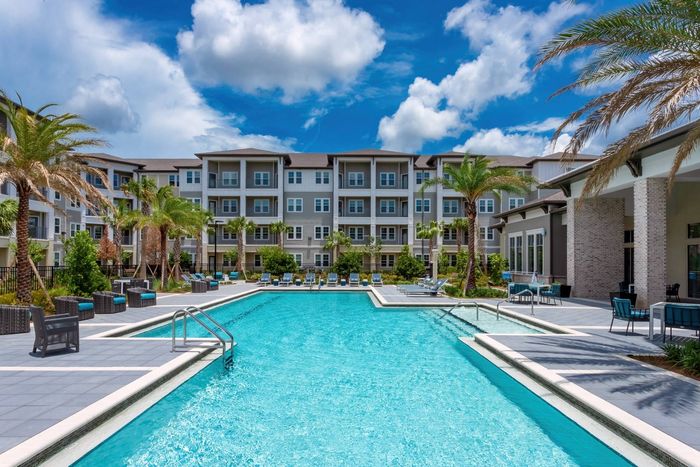 The pool area at our senior living community in Winter Garden, FL, featuring beach chairs and palm trees.