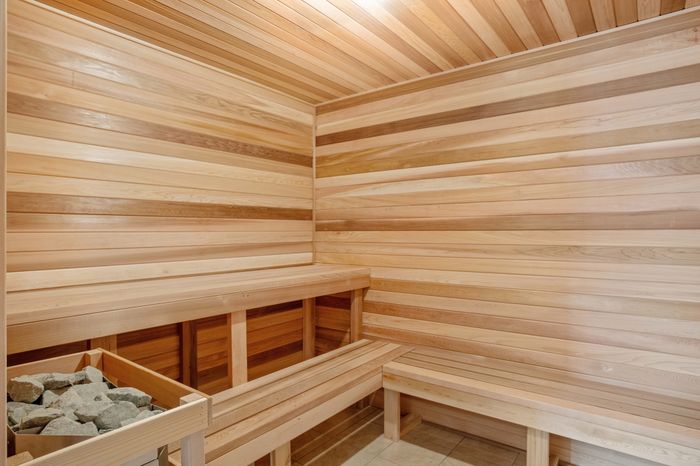 Luxurious sauna room with sleek wood paneling, featuring plush benches and a soothing ambiance.