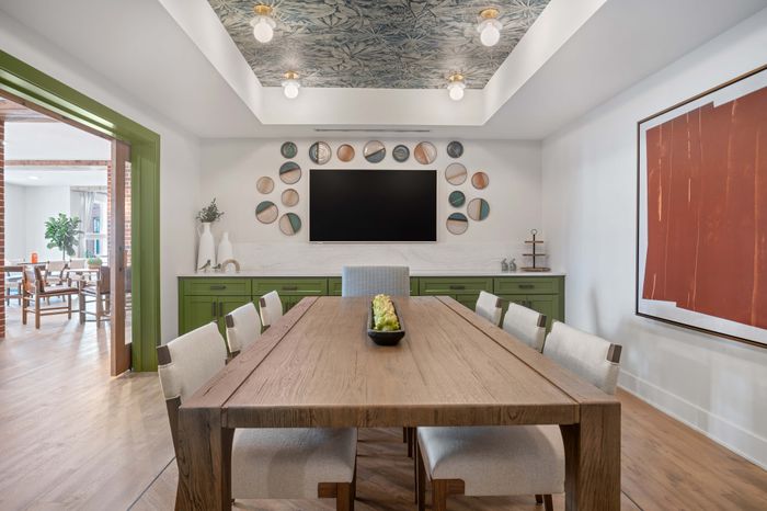 Stylish dining area with a rustic wooden table, elegant green cabinets, and artistic wall decor, creating a harmonious blend of modern and natural design.