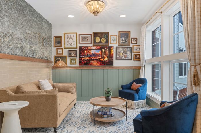 Charming living area with elegant framed artwork, plush seating, and floor-to-ceiling windows inviting natural light.