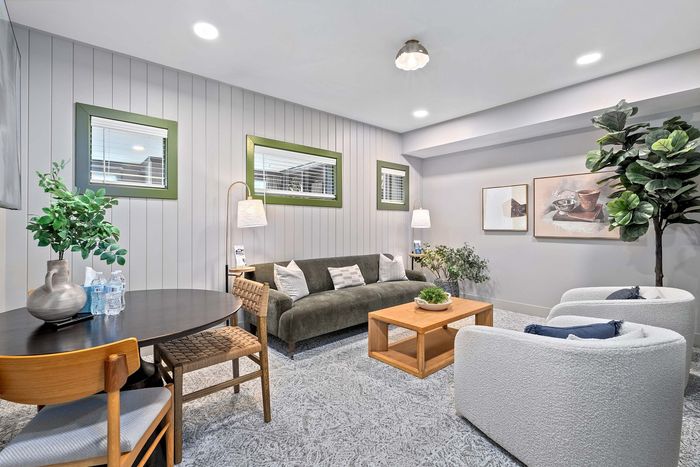 Chic and cozy living area with elegant d&eacute;cor, featuring a plush sofa, stylish art, indoor plants, and warm lighting.