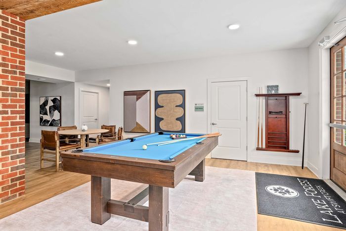 Chic entertainment room featuring a stylish pool table, modern art d&eacute;cor, and cozy seating area.