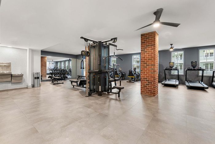 Modern apartment gym with state-of-the-art equipment, featuring treadmills, weight machines, and a sleek design for optimal workouts.