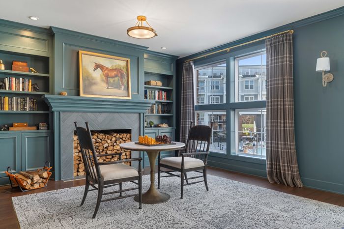 Elegant living room with a vintage charm, featuring a cozy fireplace, built-in bookshelves, and a serene view from large windows.