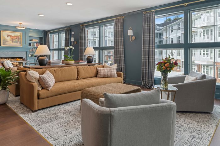 Inviting living room with elegant decor featuring a plush brown sofa, stylish armchairs, and a cozy fireplace, bathed in natural light from expansive windows.