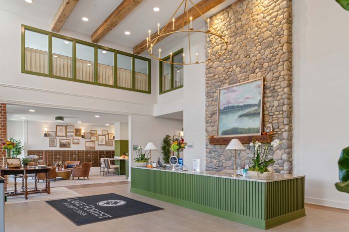 Charming apartment lobby featuring a stunning stone wall with artwork, elegant chandelier, and stylish green accents, creating an inviting and luxurious atmosphere.