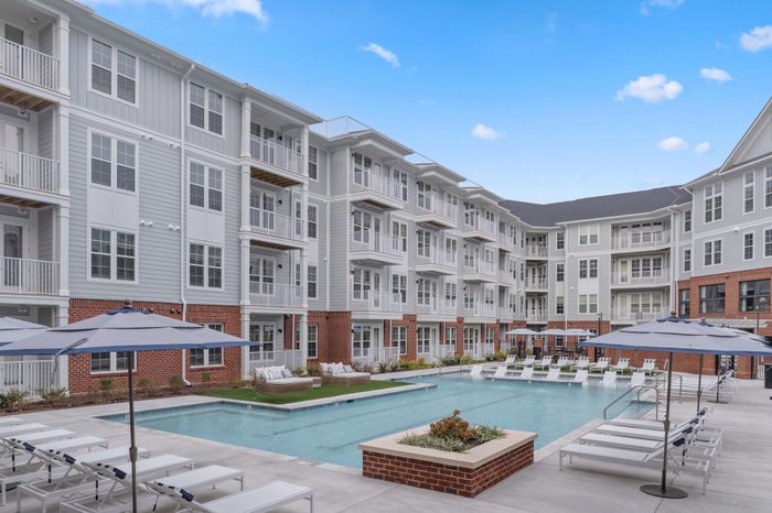 Elegant apartment complex featuring a modern swimming pool and stylish sun loungers, perfect for relaxation.
