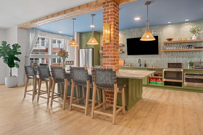Chic open kitchen featuring a stylish breakfast bar with woven chairs, modern appliances, and decorative shelving under warm pendant lighting.