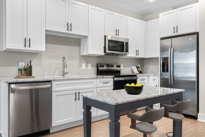 Modern kitchen with chic white cabinetry, stainless steel appliances, and a stylish island with contemporary seating.