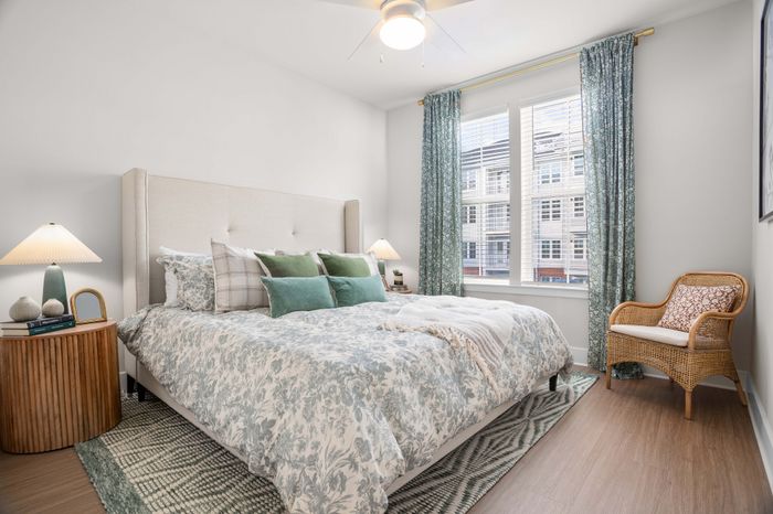 Inviting bedroom with elegant decor featuring a plush bed, stylish patterned duvet, and abundant natural light through large windows. Perfect for comfort and relaxation.