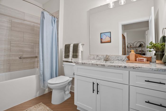 Charming bathroom featuring marble countertop, modern vanity, and serene light blue shower curtain.