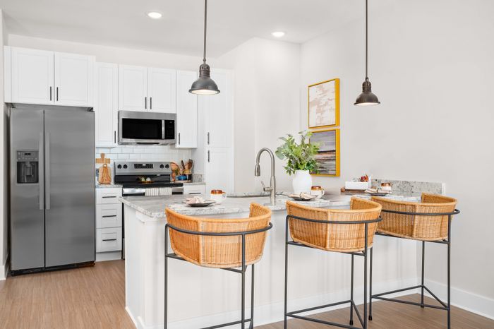 Modern kitchen with sleek stainless steel appliances, white cabinets, and an inviting breakfast bar with elegant wicker stools.
