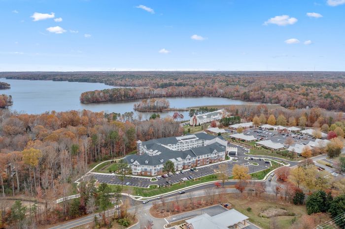 Breathtaking aerial view of a serene lakeside residential community surrounded by vibrant autumn foliage, offering a tranquil and picturesque living experience.